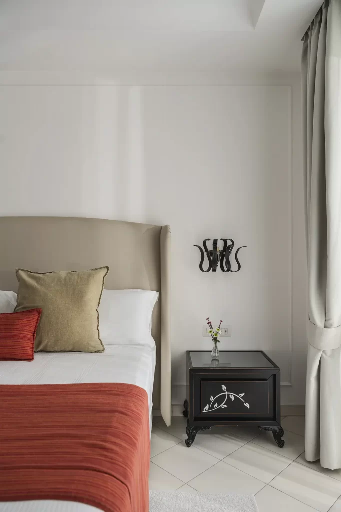 Camera moderna con letto, cuscini colorati e comodino elegante.