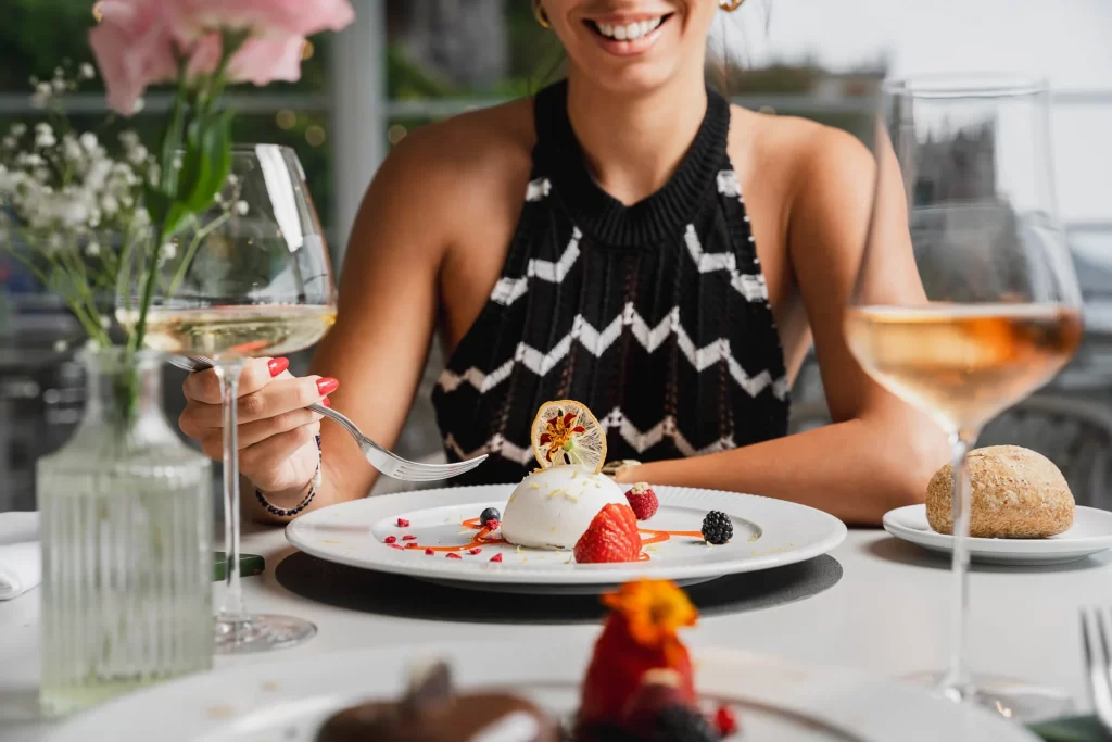 Donna sorridente che gusta un dessert raffinato in un ristorante elegante.