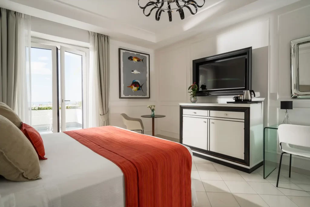 Camera d'albergo moderna con letto matrimoniale, coperta arancione e televisore a schermo piatto.