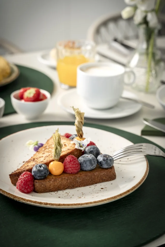Fetta di torta guarnita con frutti di bosco su un piatto elegante.