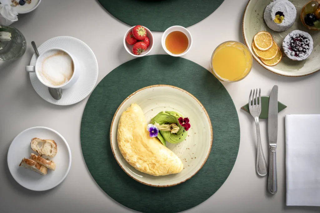 Colazione elegante con omelette, frutta, succo d'arancia e cappuccino.
